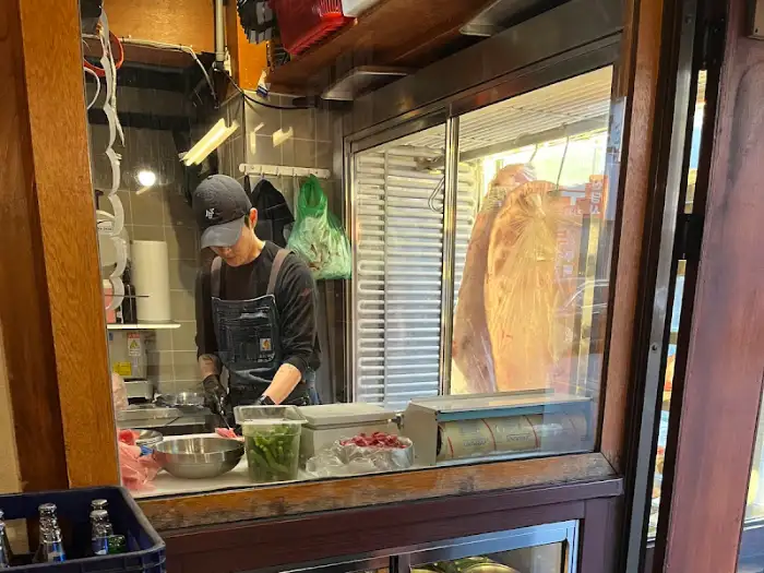 주방 안에서 남성 직원이 고기를 정형하고 있는 모습.