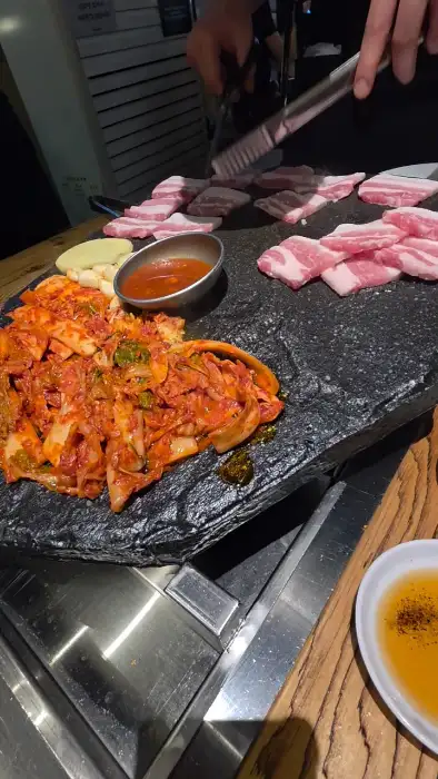 직원이 가위와 집게로 고기를 자르는 모습