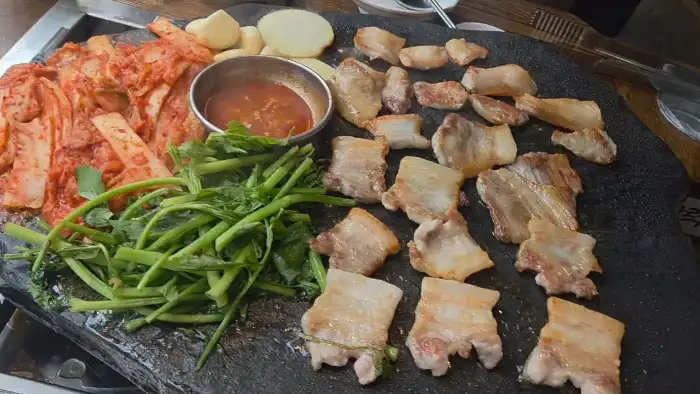 잘 구워진 고기와 김치, 채소가 놓인 돌판
