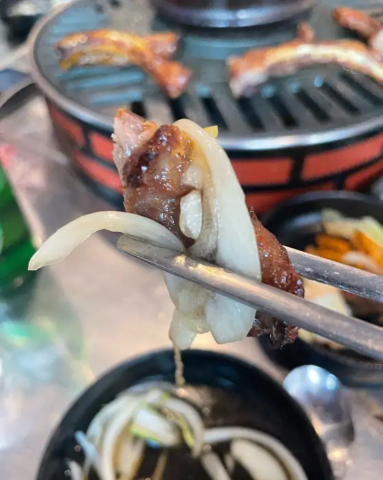 양파와 함께 쪽갈비를 집어 먹는 모습