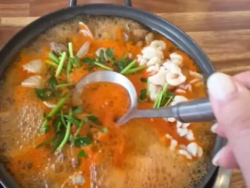 끓고 있는 알찜 냄비와 국자를 든 손