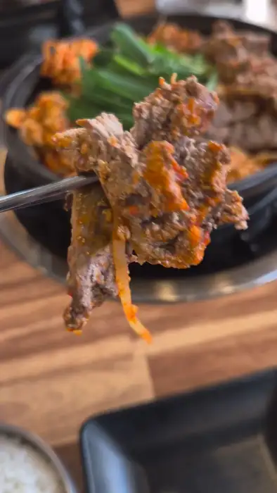 젓가락에 집은 매콤한 양념의 고기 조각