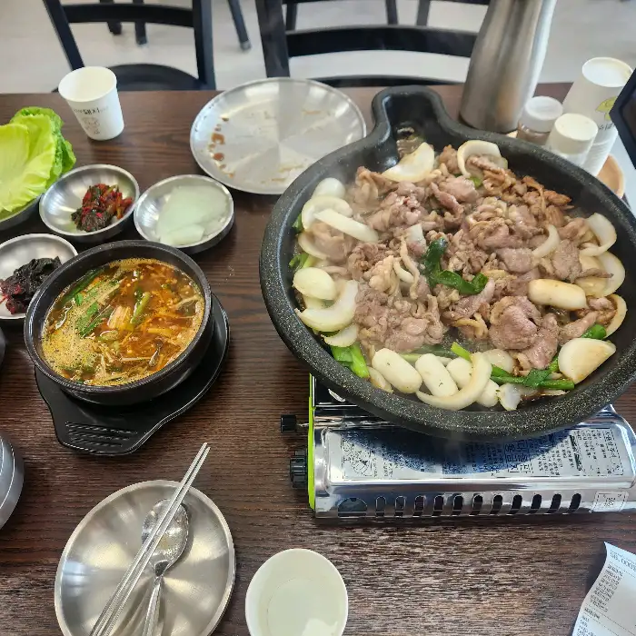 사랑채덕 평창오대산점의 오리 주물럭과 오리탕, 반찬이 차려진 식탁 모습