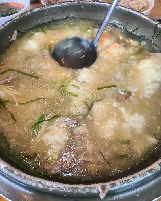 오리백숙에 팽이버섯, 파, 찹쌀 등이 푸짐하게 담겨 있는 모습