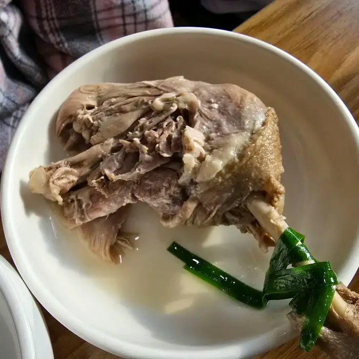 흰 접시에 담긴 푸짐한 오리 백숙 조각