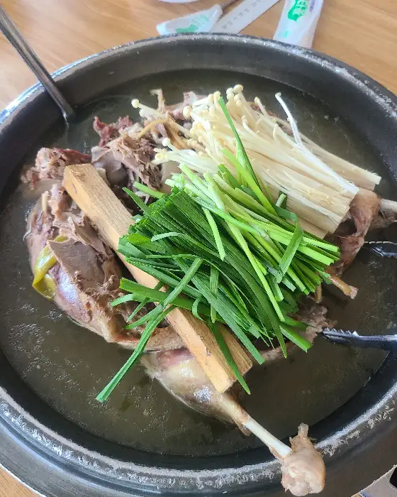 오리진흙구이 솥에 팽이버섯, 파, 나무토막 등이 함께 곁들여진 모습