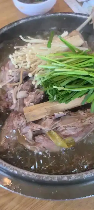 오리진흙구이 솥에 팽이버섯, 파, 나무토막 등이 함께 곁들여진 모습