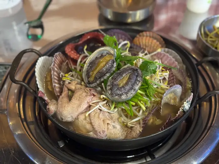 해돈집 해신탕에 푸짐하게 담긴 전복, 가리비, 문어와 닭고기