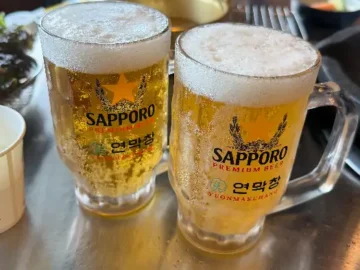 시원한 맥주잔 두 개가 테이블 위에 놓여있는 모습