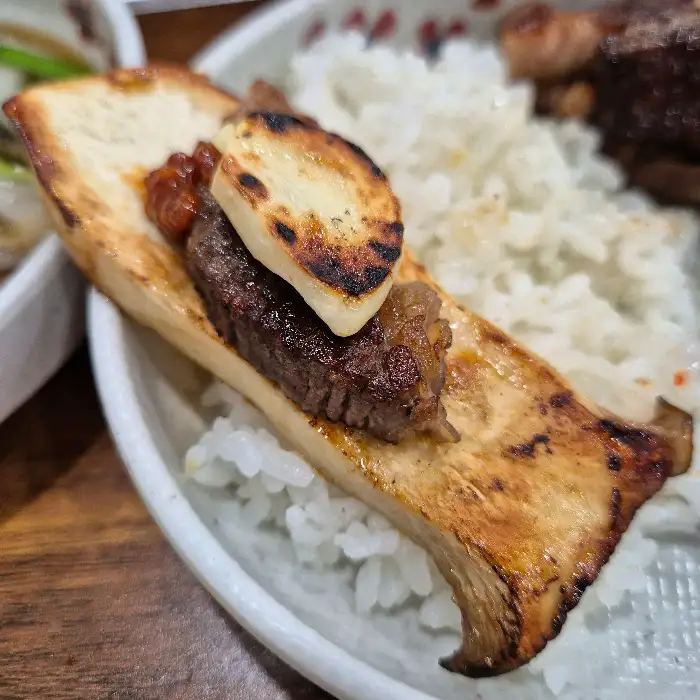 고기 한 점과 버섯, 밥이 함께 담긴 접시