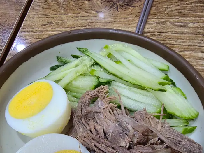 비빔밀면에 곁들여지는 고기 고명과 오이, 삶은 달걀