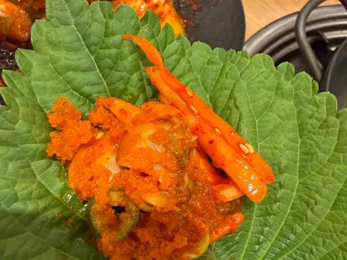 깻잎 위에 얹어진 만세양념꼬막과 날치알