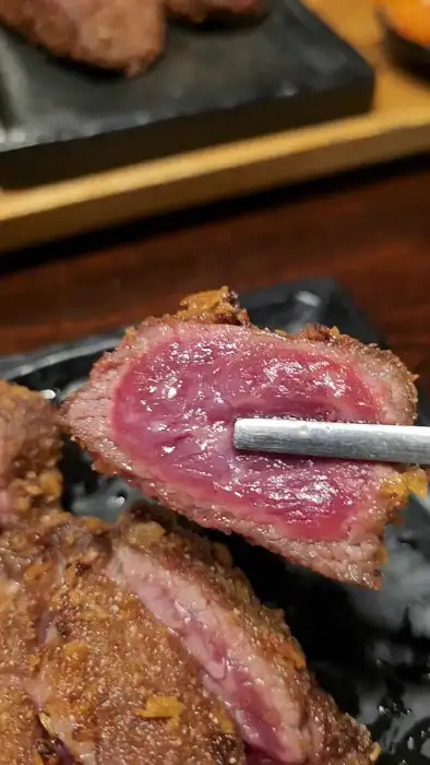 젓가락으로 규카츠 한 점을 집어 화로에 올리는 모습