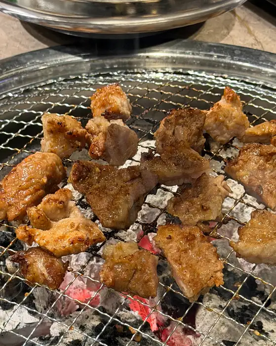 오돈의 두툼한 삼겹살이 숯불 위에서 맛있게 익어가고 있습니다.