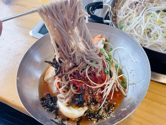 평창댁 메밀막국수의 쫄깃한 메밀면을 들어올리는 모습
