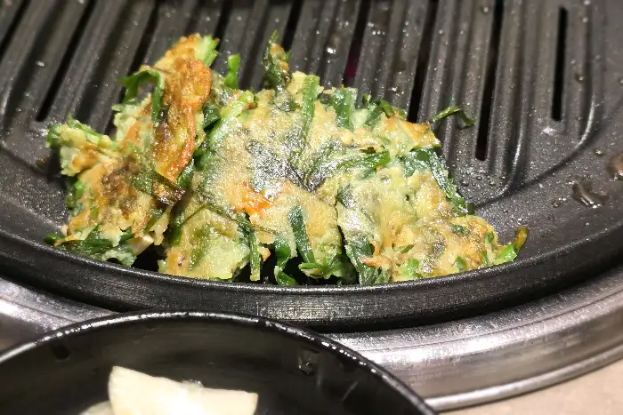 오돈의 바삭한 파전이 숯불 위에서 먹음직스럽게 구워지고 있습니다.