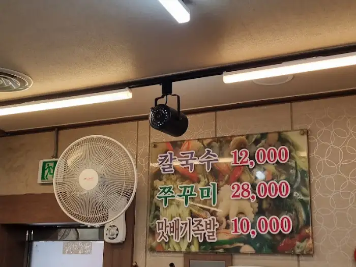 벽에 걸린 메뉴판에 칼국수 12,000원, 쭈꾸미 28,000원 등의 가격이 명시된 모습