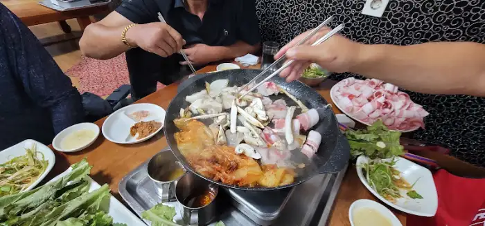 가스 철판 위 삼겹살, 버섯, 마늘, 양파 등과 함께 구워지는 모습