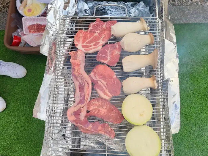 무수아취 캠핑장에서 숯불 위에 구워지고 있는 신선한 고기와 버섯, 양파