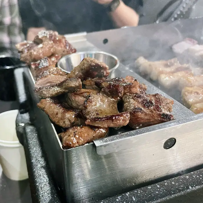 금돈집 광명하안점에서 제공되는 두툼하게 썰린 삼겹살이 불판 위에서 구워지고 있는 모습