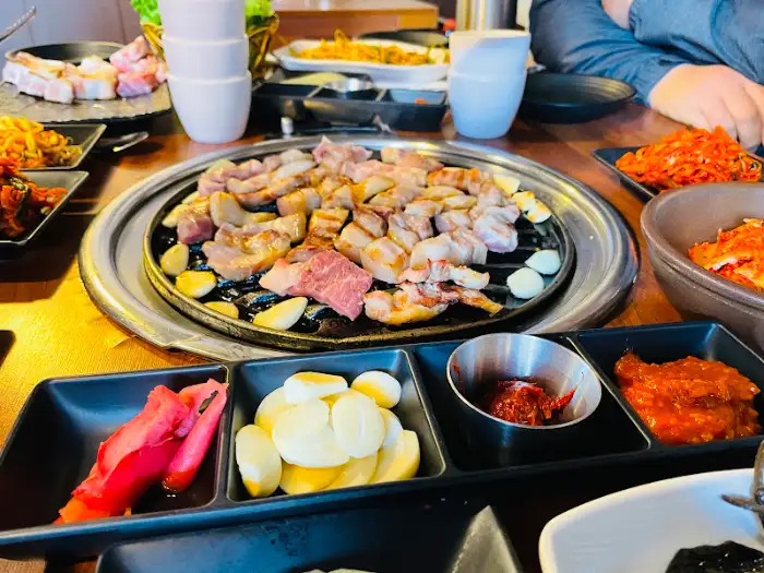 식탁 위에 차려진 삼겹살 구이와 밑반찬