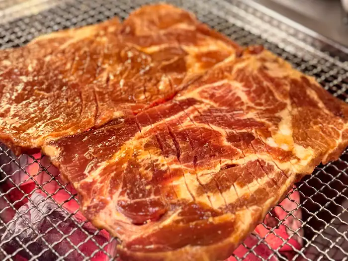 불판 위에서 맛있게 구워지고 있는 양념이 살짝 된 두툼한 돼지고기