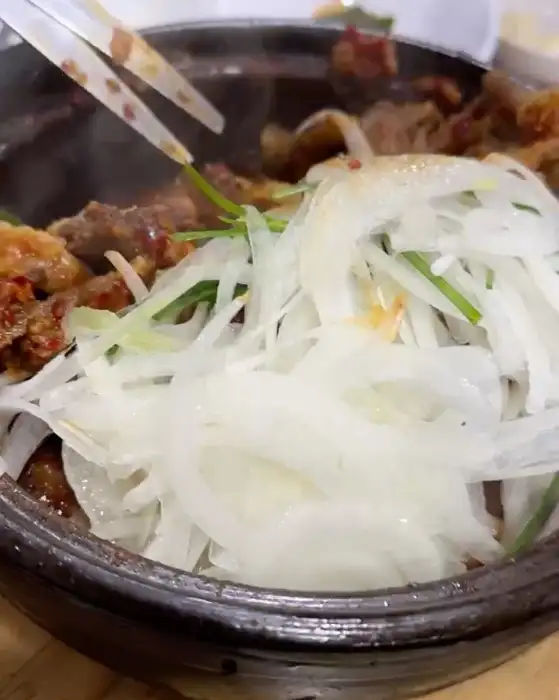 뜨겁게 끓고 있는 갈비찜의 모습으로, 빨간 양념 국물이 자작하게 담겨 있습니다.