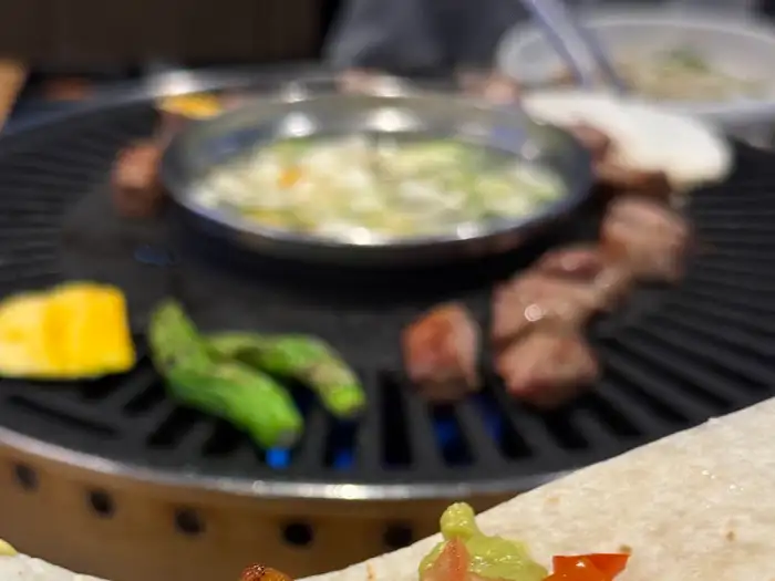 숯불 그릴 위에서 지글지글 익어가는 고기와 곁들임 음식들