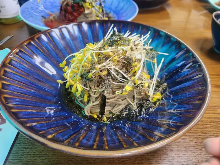 푸른색 톤의 깊은 그릇에 담긴 메밀 막국수가 풍성한 고명과 함께 나온 모습