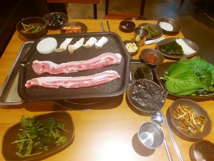 구워지고 있는 삼겹살과 신선한 쌈 채소가 차려진 대관령쌈밥 테이블