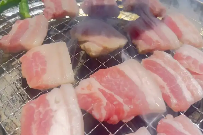 두툼한 삼겹살 조각들이 참숯 위에서 구워지고 있는 모습