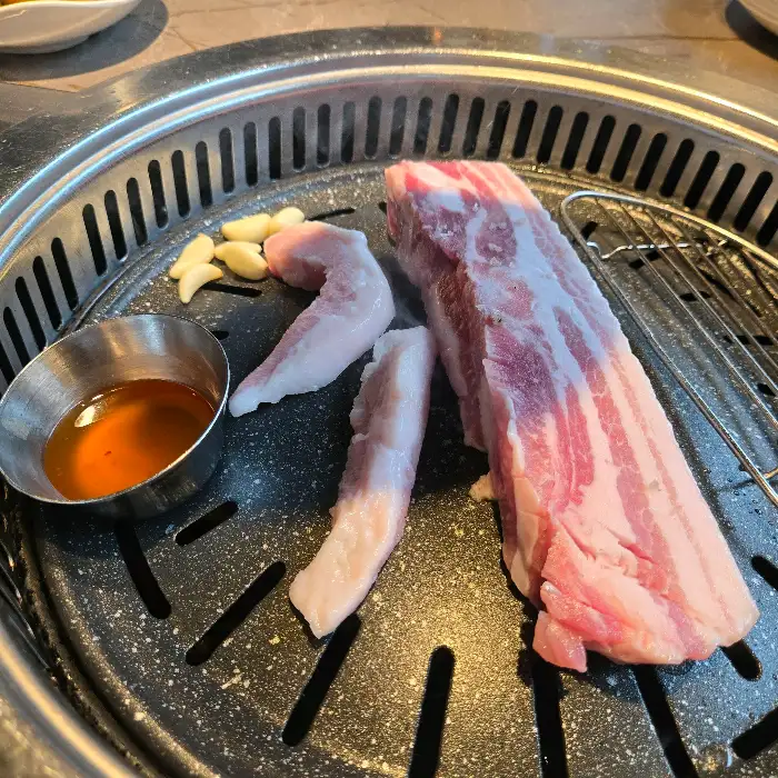 불판 위에서 익어가고 있는 두툼한 삼겹살 덩어리