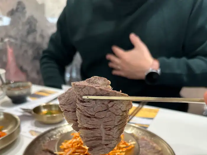 집게로 집어 올린 두툼한 수육 조각