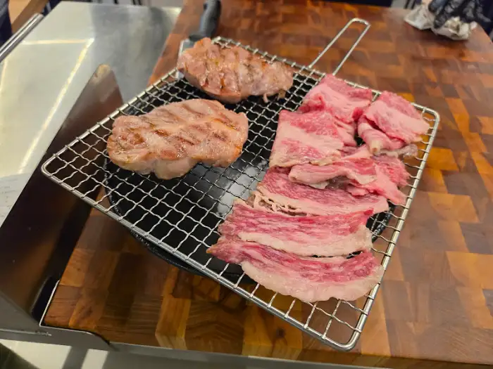 철제 꼬치에 담겨 숯불 위에서 구워지고 있는 여러 종류의 돼지고기