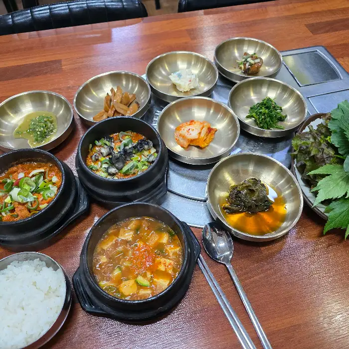 다양한 뚝배기 요리와 쌈 채소가 함께 제공되는 식사 모습