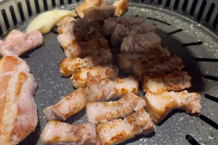 잘 구워진 삼겹살 여러 점이 불판 위에 놓여 있는 모습