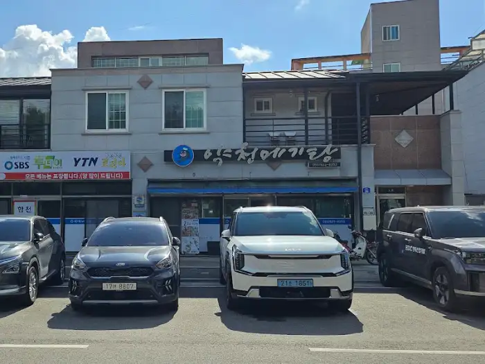 낮에 보이는 약천메기탕 건물과 주차된 차량들